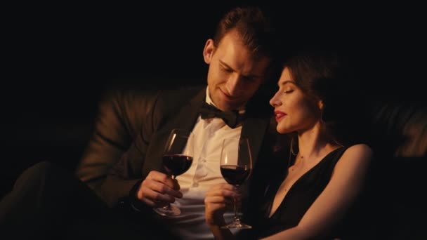 Glückliches Paar schaut einander an und klirrt mit Brille auf schwarzem Hintergrund - Filmmaterial, Video