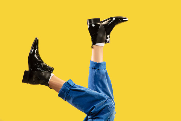 Mans legs in black stylish shoes isolated on yellow background. - Фото, зображення