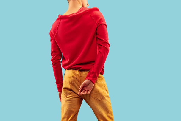 Νεαρός Καυκάσιος άνδρας με έντονα χρωματιστά ρούχα ποζάροντας σε μπλε φόντο στούντιο. - Φωτογραφία, εικόνα