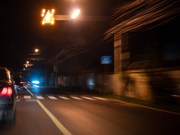 Zoom flou d'une voiture conduisant la nuit avec zone de passage de zèbre floue sur la route. - Photo, image