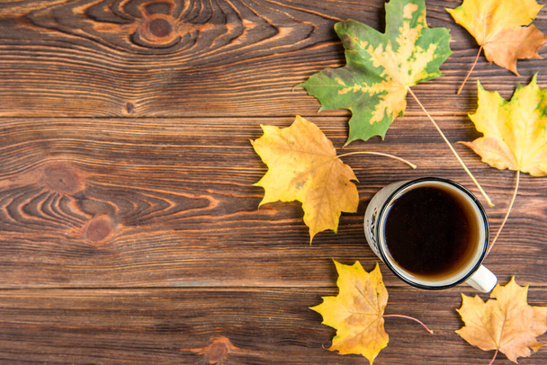 Tea cup and autumn leaves on wooden background. Flu season in autumn, disease. - Photo, image