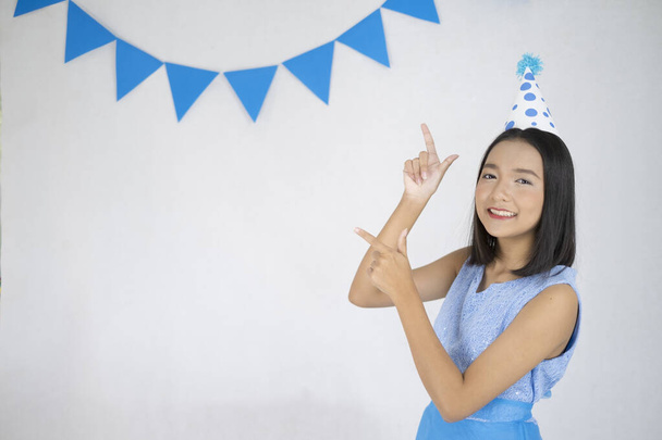 Glückliches junges Mädchen trägt blaues Kleid und Partyhut mit weißem Hintergrund. - Foto, Bild
