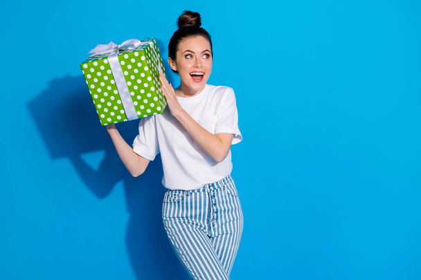 Portrait of positive crazy interested girl hold big green gift box shake want know what get 14-february 8-march celebration wear good look clothes isolated bright shine color background - Foto, Imagen