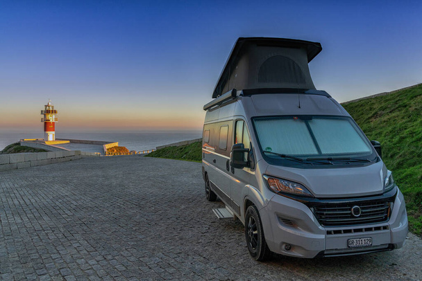 Gri karavan güneş batarken Galiçya sahilindeki Cabo Ortegal deniz fenerine park etmiş. - Fotoğraf, Görsel