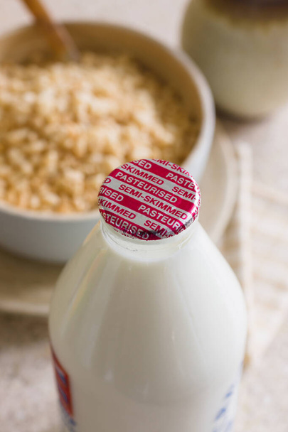 Frische teilentrahmte Milch in einer recycelbaren Glasflasche, die Schritt für Schritt von einem traditionellen Milchmann zur Tür geliefert wird - Foto, Bild