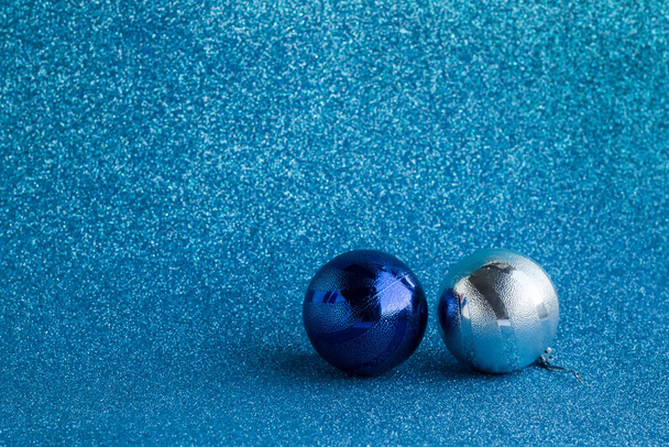 Zwei glänzende Weihnachtskugeln auf silbrig blauer Oberfläche mit Kopierraum - Foto, Bild
