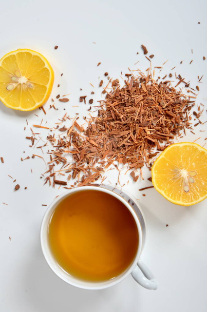 Taza de té, corteza de Catuaba y limón sobre fondo blanco. Té de hierbas natural de corteza de árbol de Catuaba, afrodisíaco natural de Brasilia - Foto, imagen