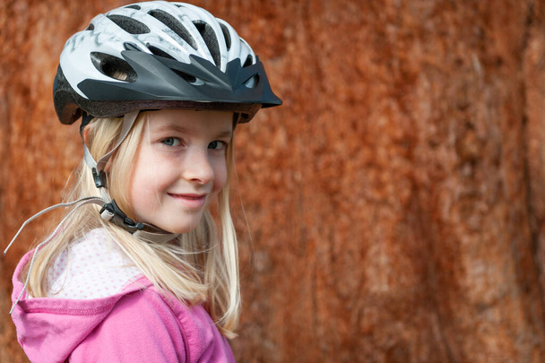 A young blonde girl poses in a cycle helmet - Fotó, kép