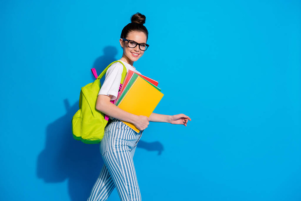 Profile side photo of positive girl hold copy books go walk classroom lesson lecture library copyspace wear good look clothes isolated over bright shine color background - Φωτογραφία, εικόνα