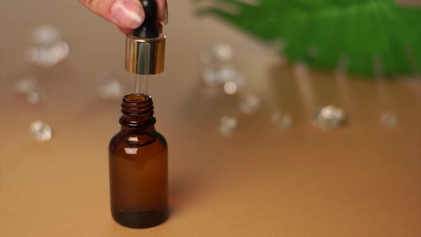 a bottle of natural cosmetic oil. in dark glass, on a dark beige plain background. the concept of beauty and self-care. - Footage, Video