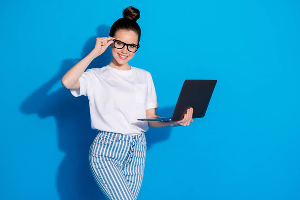 Portrait of her she nice attractive pretty smart clever skilled cheerful cheery girl holding in hand laptop touching specs part-time isolated on bright vivid sine vibrant blue color background - Photo, image