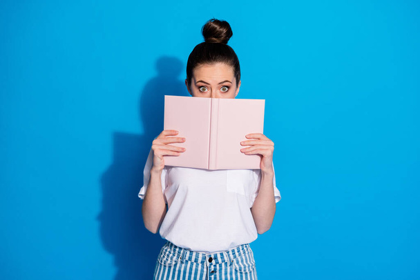 Portrait of her she nice attractive pretty scared girlish girl reading story hiding behind book knowledge isolated on bright vivid shine vibrant blue color background - Foto, afbeelding