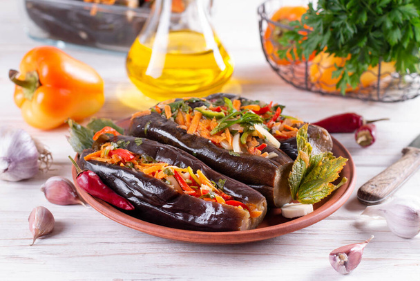 Pickled stuffed eggplant with vegetables in a plate on a white wooden table - Photo, Image