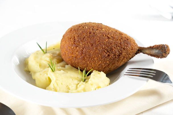 Cutted chicken cutlet in bread crumbs stuffed with butter and herbs, served with mashed potato, on a white background, horizontal - Φωτογραφία, εικόνα