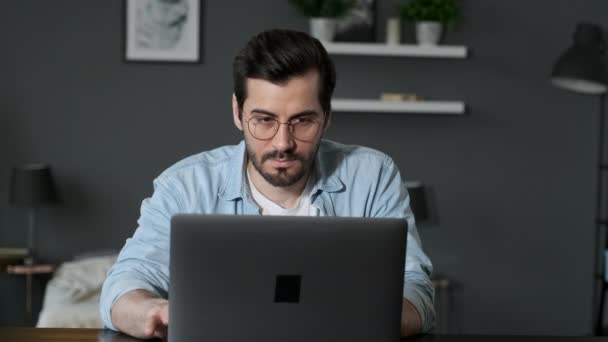 Young Man Freelancer mit Laptop, Tippen, Scrollen, Surfen im Web, Blick auf den Bildschirm. Kreativer Millennial am Schreibtisch im Home Office - Filmmaterial, Video