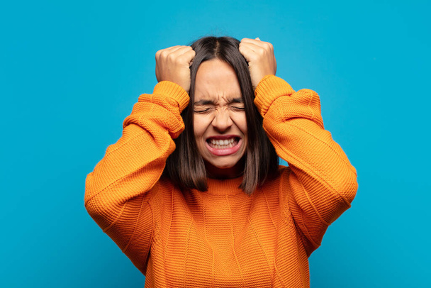 hispanic woman feeling stressed and anxious, depressed and frustrated with a headache, raising both hands to head - Foto, imagen