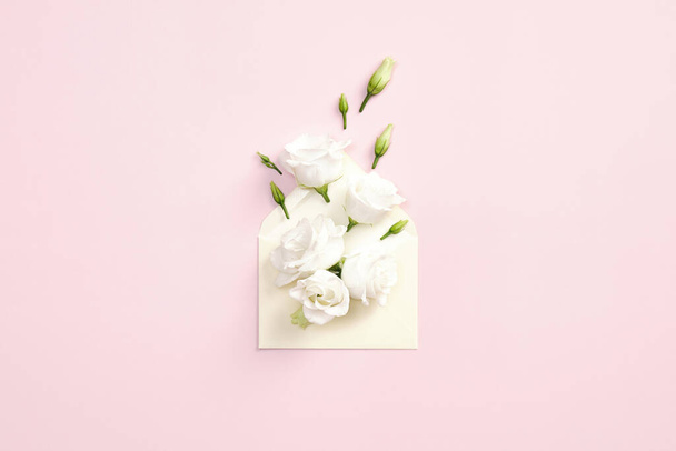 Roses flowers in envelope on pink background. Birthday gift, Valentine day creative present, Mothers Day surprise concept. - 写真・画像