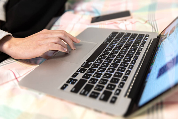 Bureau à domicile et concept de télétravail. Une jeune femme travaille sur un ordinateur à distance à la maison alors qu'elle est assise sur un canapé pendant la pandémie de coronavirus. - Photo, image