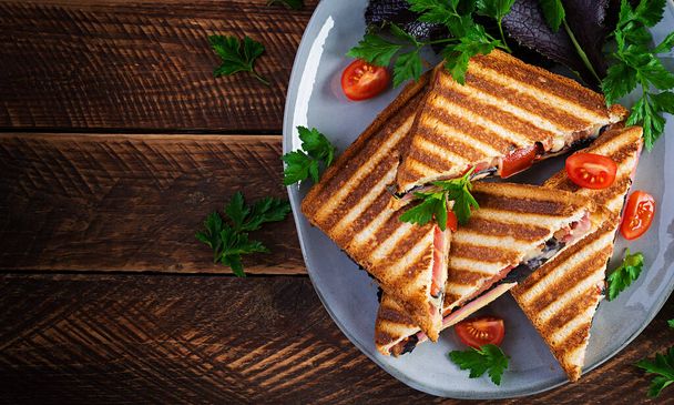Gegrillte Club-Sandwich-Panini mit Schinken, Tomaten, Käse und Blattsenf. Leckeres Frühstück oder Snack. Draufsicht, Kopierraum, Overhead - Foto, Bild