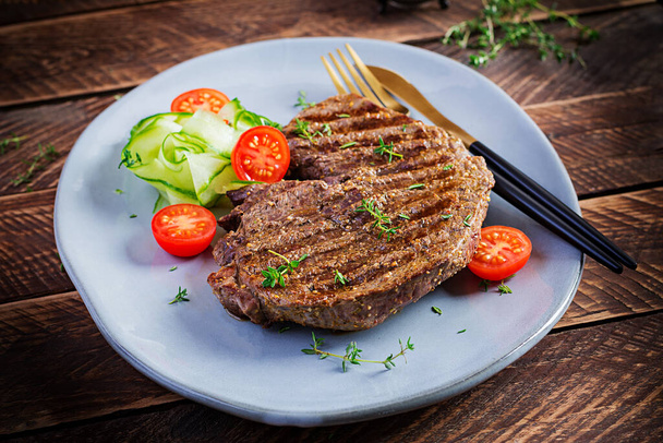 Gegrilltes saftiges Steak medium rare Rindfleisch mit Gewürzen und frischem Salat. - Foto, Bild