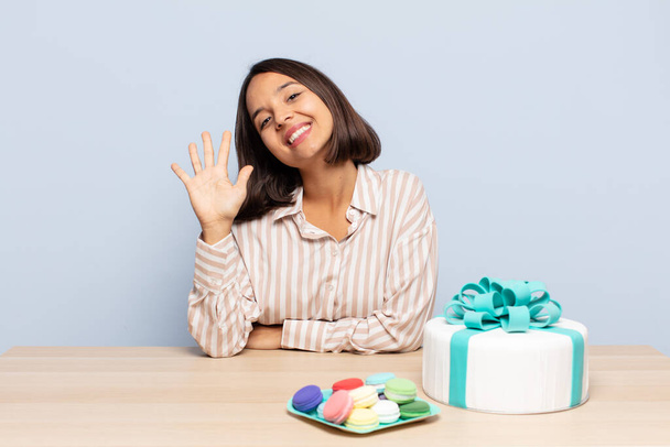 hispanic woman smiling and looking friendly, showing number five or fifth with hand forward, counting down - Foto, imagen