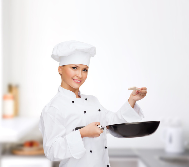 Smiling female chef with pan and spoon - Foto, afbeelding