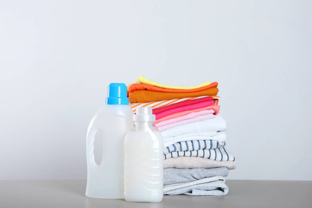 Μπουκαλάκια απορρυπαντικού ρούχων και ρούχα στο τραπέζι. Οικιακές χημικές ουσίες - Φωτογραφία, εικόνα