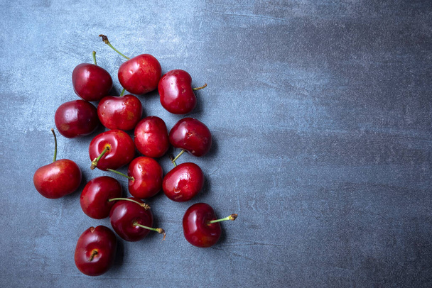 Ripe sweet cherry spread on a blue background. seen from above. Free space for edits. - Fotoğraf, Görsel