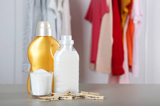 Бутылки для стирального порошка и одежда на столе. Бытовые химикаты - Фото, изображение