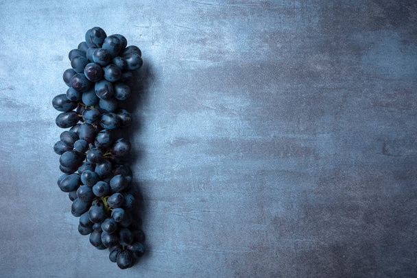 a bunch of juicy black grapes on a gray gray background, view from the top, free space for text. - Photo, Image