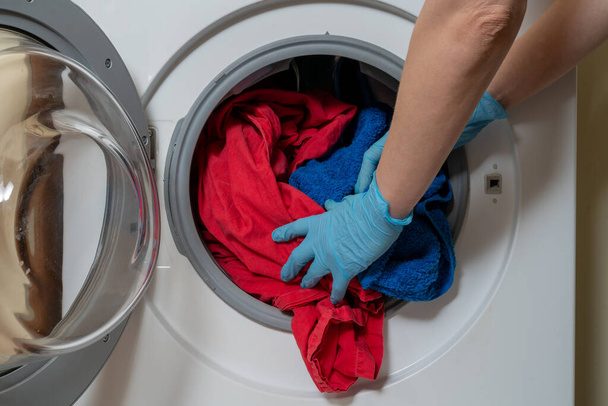 woman in gloves getting clean clothes from washing machine - Photo, Image