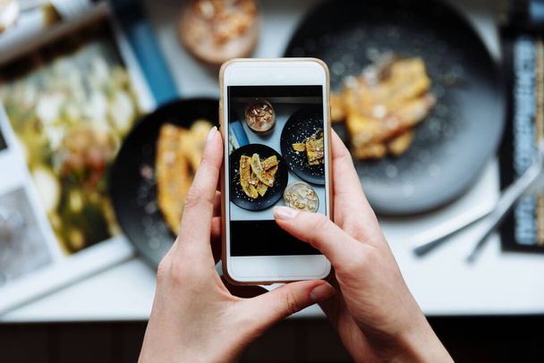 女性はスマートフォンで朝食の写真を撮る,携帯電話を手に,上のフレーム - 写真・画像