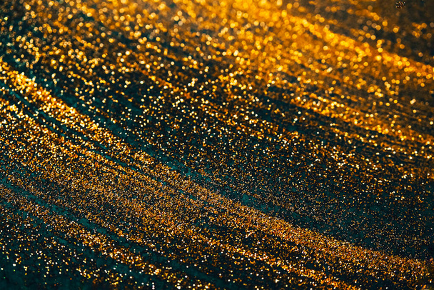 Gold glitter on dark green bokeh abstract light defocused background. - Photo, Image