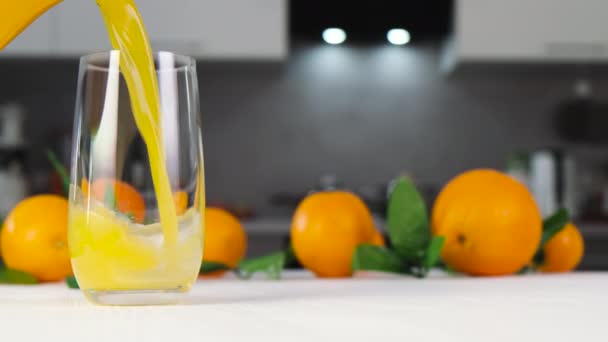 Orange juice pouring into glass on white table - Footage, Video