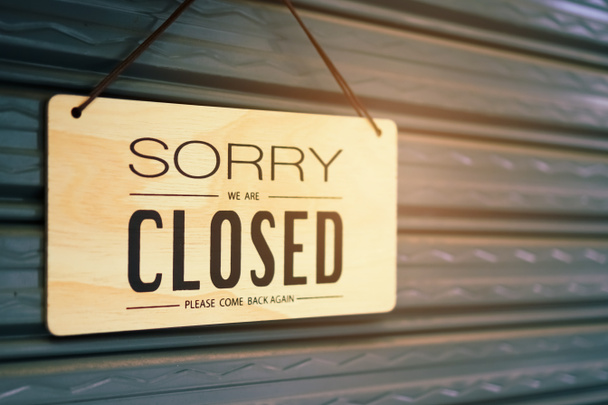 Μια πινακίδα του συγγνώμη είμαστε κλειστά κρέμονται στην πόρτα του καταστήματος επιχειρήσεων με πράσινο φόντο τη φύση - Φωτογραφία, εικόνα