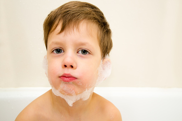 Little boy with foamy beard inflated cheeks in bathroom - Photo, Image