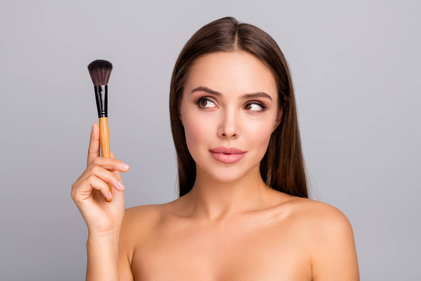 Portrait of curious interested girl hold blusher look think decide need she apply for business beauty preparation isolated over grey color background - Foto, imagen