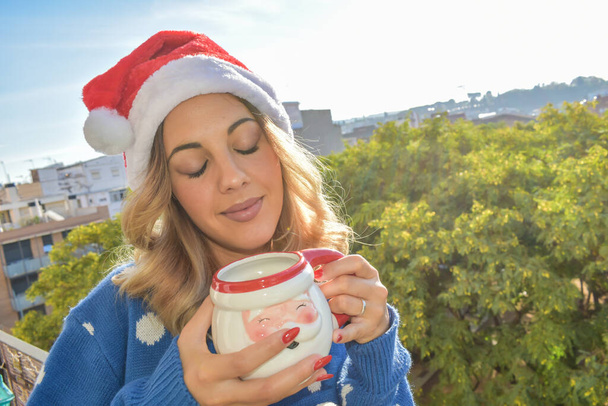 Dívka s kávou na balkóně na sobě vánoční oblečení. - Fotografie, Obrázek