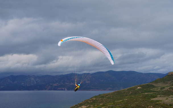 Αλεξίπτωτο πλαγιάς που πετά πάνω από τη θάλασσα στα βουνά στη νότια Σαρδηνία - Φωτογραφία, εικόνα
