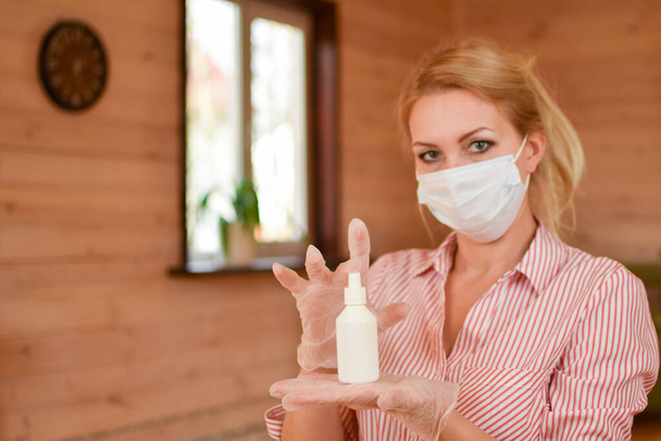 woman in a medical mask disinfects her hands. protection measures against coronavirus. - 写真・画像