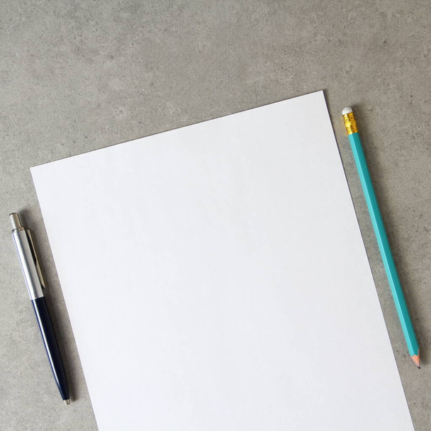 Template of white paper with a ballpoint pen and simple pencil on light grey concrete background. Concept of new idea, business plan and strategy, development and implementation of content. Stock photo with empty space for text. - Fotoğraf, Görsel