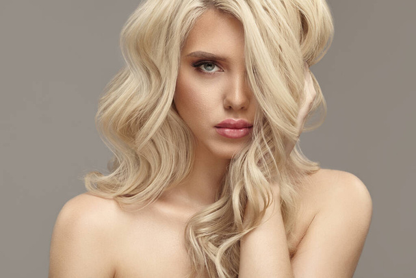 Beautiful girl with volume wavy long hair blonde has a natural hairstyle of wavy curly - Fotó, kép