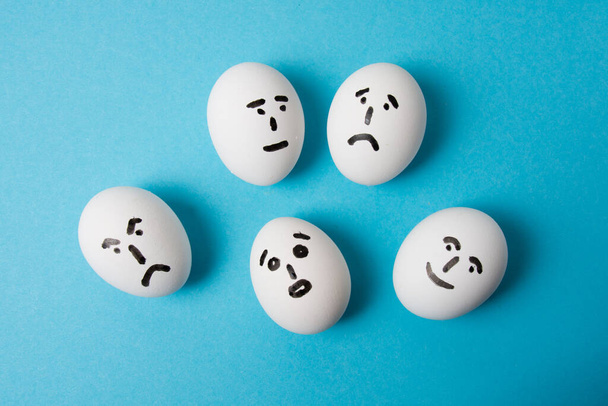 Яйца с разными эмоциями: неожиданностью, равнодушием, грустью, гневом и радостью. Изолировать на синем фоне - Фото, изображение