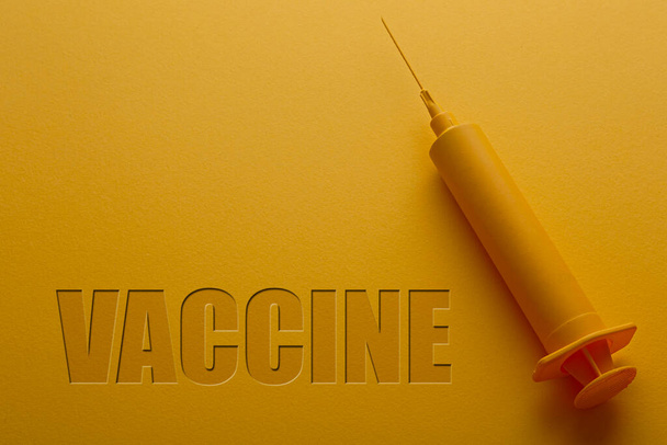 Sárga hátterű fecskendő a vakcina szóval. - Fotó, kép