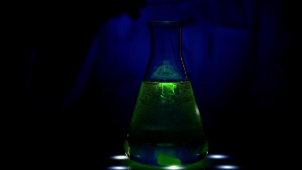 Valon aiheuttama reaktio, jonka eurooppalainen naistutkija suorittaa kemian laboratoriossa UV-valossa 4K-videossa farmaseuttiseen tarkoitukseen - Materiaali, video