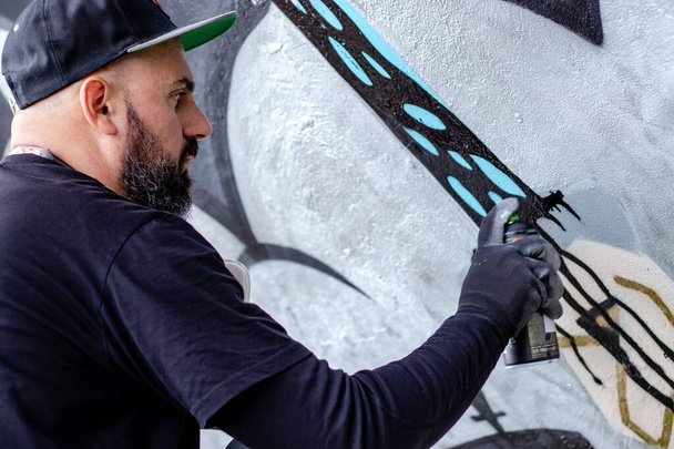 Graffiti καλλιτέχνης σε δράση, σχέδιο στον τοίχο με σπρέι αεροζόλ χρώμα σε ένα κουτί. Τέχνη του δρόμου έννοια του πολιτισμού. - Φωτογραφία, εικόνα