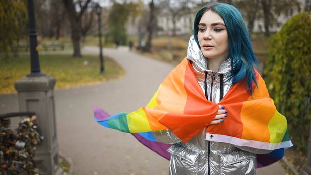 Donna lesbica con capelli verdi che cammina con grande bandiera arcobaleno - Foto, immagini