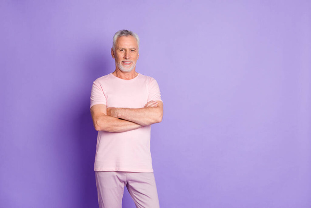 Photo of cool old man beaming smile folded arms look camera wear pink trousers t-shirt isolated violet color background - Zdjęcie, obraz