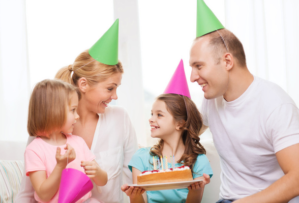 Smiling family with two kids in hats with cake - Foto, afbeelding