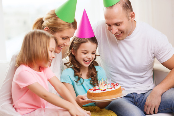Smiling family with two kids in hats with cake - Photo, image